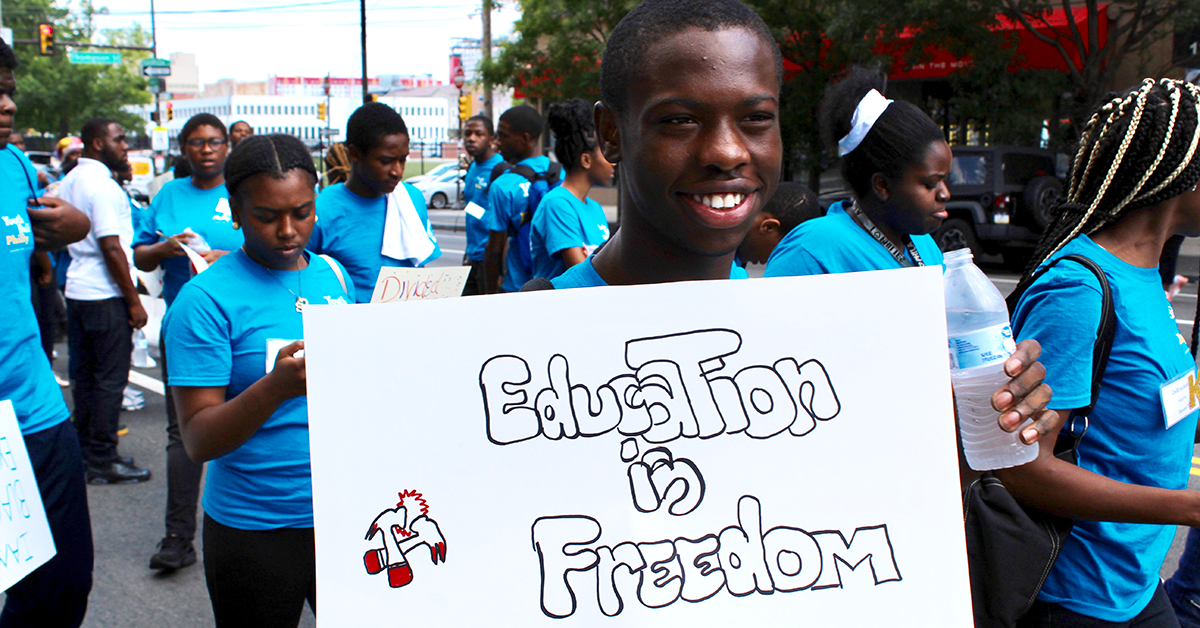 YouthBuild student holds a sign that says Education is Freedom.