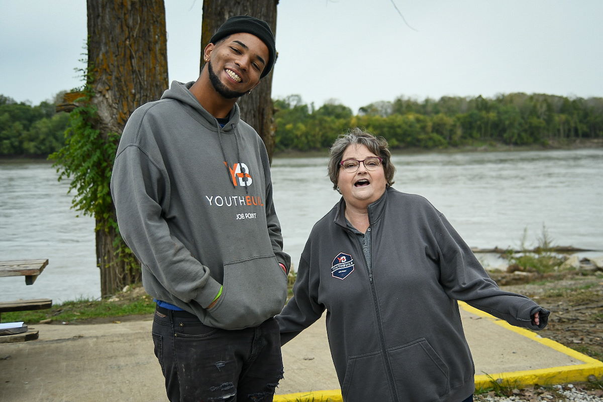 Two people standing together near lake smiling