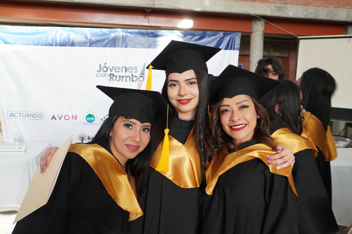 Three people in graduation robes and hats standing together and smiling